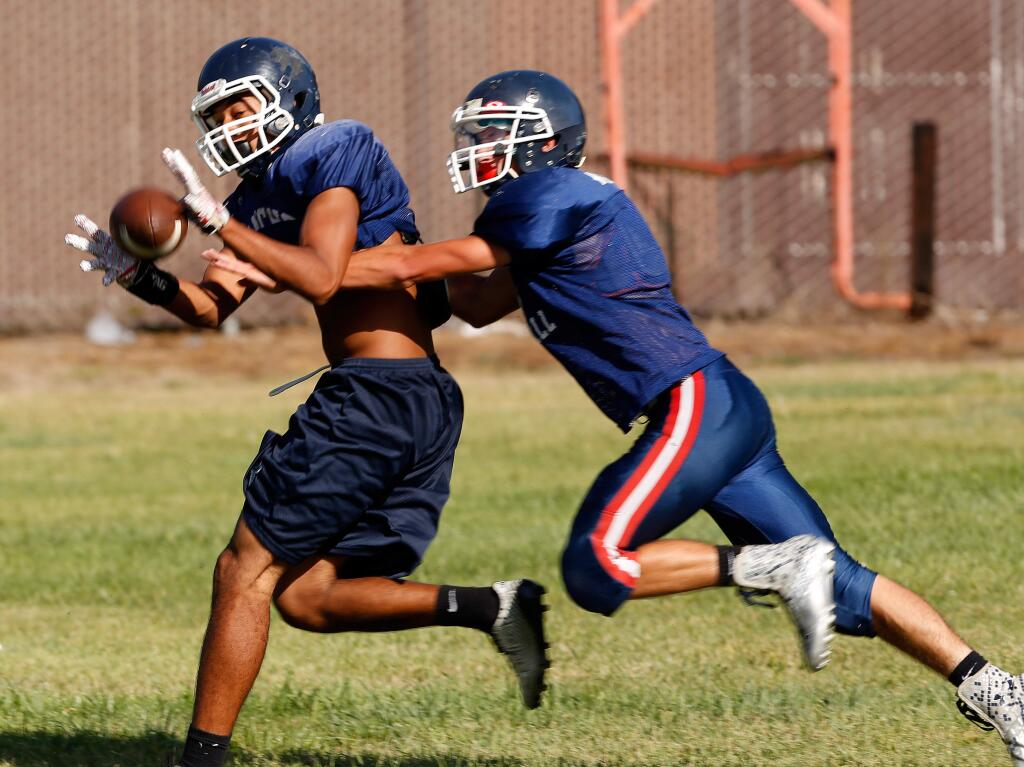 Chris Taylor-Yamanoha, left, makes a catch while defended by CJ Wagner in a scrimmage with junior varsity during football practice at Rancho Cotate high school in Rohnert Park, California on Tuesday, September 1, 2015.