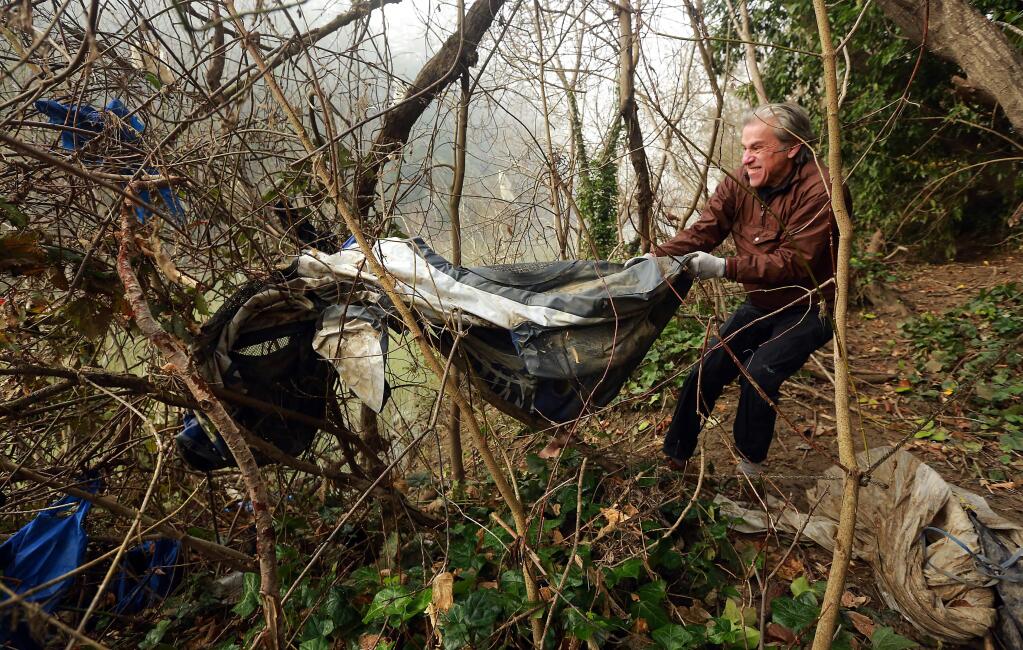 David Bedford of Healdsburg struggles to remove an old rubber boats from a tree along the Russian River in Guerneville during a clean up effort sponsored by the Russian Riverkeeper. (photo by John Burgess/The Press Democrat)
