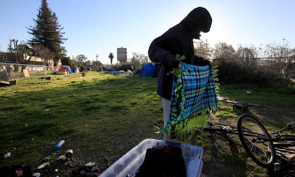 Edmund Wilson thoughtfully clears his encampment along the Joe Rodota Trail after Sonoma County Regional Parks officials gave a group experiencing homelessness an 8 a.m. deadline to move off the trail on Wednesday, Feb. 24, 2021, in Santa Rosa. (Kent Porter / The Press Democrat)
