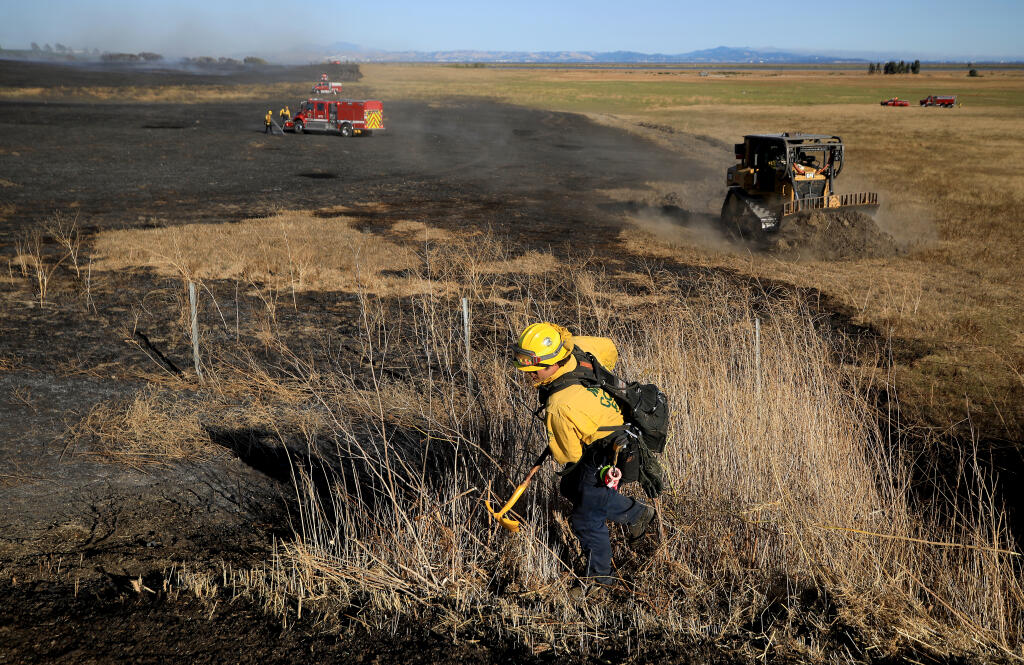 Firefighters with North Bay Fire and Marin County Fire, work to extinguish remains hot spots after a quick, wind driven brush fire burned 50 acres off Highway 37, Wednesday, July 27, 2022 near Sonoma Raceway. (Kent Porter / The Press Democrat) 2022