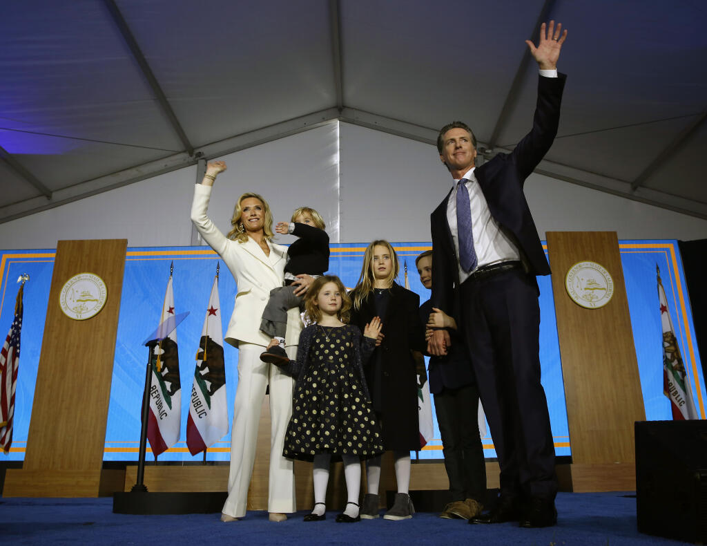 FILE - In this Monday, Jan. 7, 2019 file photo, California Governor Gavin Newsom, right, his wife, Jennifer Siebel Newsom, left, and children wave after taking the oath office during his inauguration as 40th Governor of California in Sacramento, Calif. Two of Gov. Gavin Newsom’s children have tested positive for the coronavirus and his office says the family is following “all COVID protocols.” A statement issued Friday, Sept. 17, 2021 says Newsom, his wife and two other children have since tested negative for the virus. (AP Photo/Rich Pedroncelli, File)