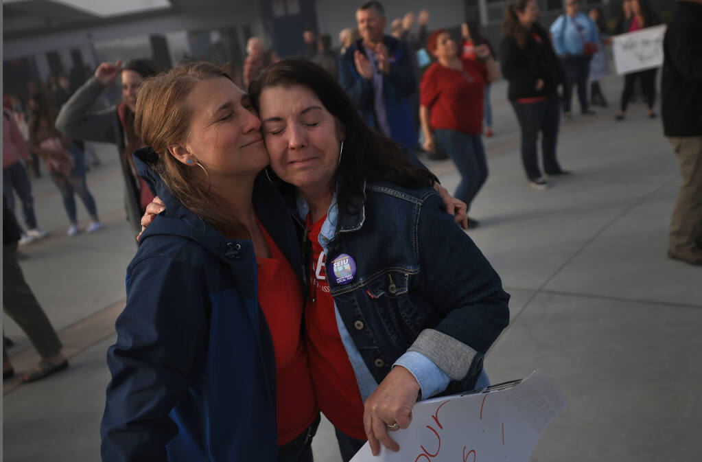 Rohnert Park Cotati Educators Association first vice president Lisa Bauman, left, and union president Denise Tranfaglia embrace at Rancho Cotate High School, Friday, March 18, 2022 as the two gather with their co-workers, welcoming students back to school after a tentative deal with Cotati-Rohnert Park district officials late Thursday night, after a six day strike. (Kent Porter / The Press Democrat) 2022