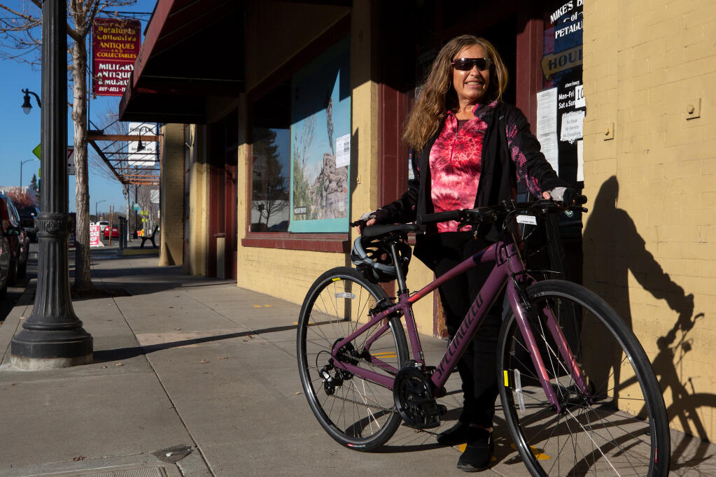 Katie Bushnell stands outside Mike's Bikes with a bicycle identical to the one she purchased with help from strangers via a GoFundMe webpage, in Petaluma, California, on Wednesday, Dec. 23, 2020. Bushnell, who has been undergoing treatment for terminal cancer, rode a bicycle for her regular transportation until her bike was stolen from in front of her apartment. (Alvin A.H. Jornada / The Press Democrat)