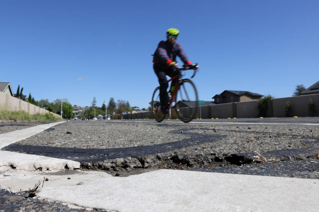 A cyclist approaches a pothole along Hopper Avenue near Crestview Drive in Santa Rosa, Calif., on Monday, April 11, 2022. (Beth Schlanker / The Press Democrat)