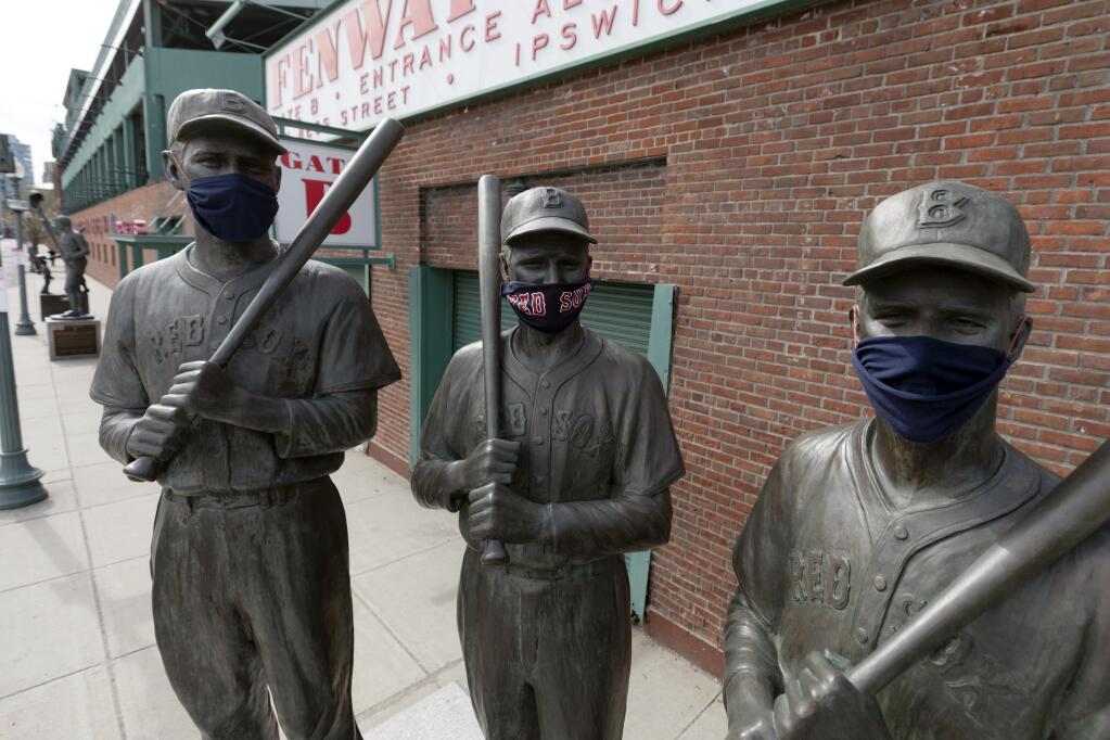 Statues of former Boston Red Sox greats, from left, Ted Williams, Bobby Doerr and Johnny Pesky, feature protective masks outside Fenway Park, Friday, April 17, 2020, in Boston. (Michael Dwyer / ASSOCIATED PRESS)