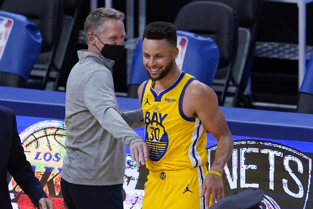 Golden State Warriors head coach Steve Kerr, left, celebrates with guard Stephen Curry after the Warriors defeated the Milwaukee Bucks in San Francisco on Tuesday, April 6, 2021. (Jeff Chiu / ASSOCIATED PRESS)