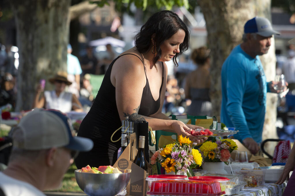 Dana Benton sets a table overflowing with food, flowers and wine at the annual Sonoma City Party on the Plaza on Thursday, August 4, 2022. (Robbi Pengelly/Index-Tribune)