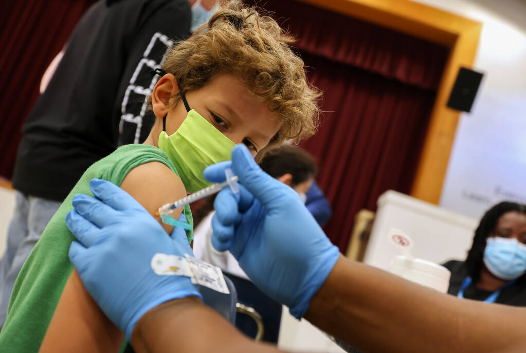 Koa Grant, 7, watches the needle enter his arm as he receives his second dose of the Pfizer-BioNTech COVID-19 vaccine during a clinic at Kawana Elementary School in Santa Rosa on Tuesday, Dec. 7, 2021. (Christopher Chung / The Press Democrat)