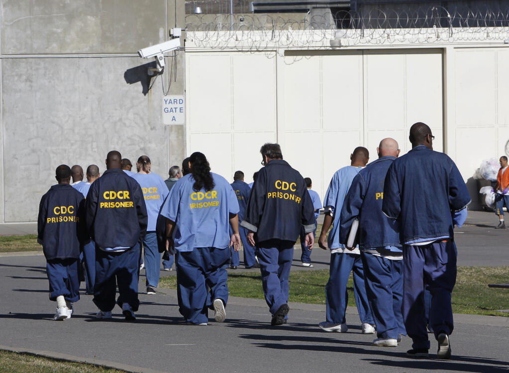 FILE - In this Feb. 26, 2013, file photo, inmates walk through the exercise yard at California State Prison Sacramento, near Folsom, Calif. California is giving 76,000 inmates, including violent and repeat felons, the opportunity to leave prison earlier as the state aims to further trim the population of what once was the nation's largest state correctional system. The new rules take effect Saturday, May 1, 2021, but it will be months or years before any inmates go free earlier.   (AP Photo/Rich Pedroncelli, File)