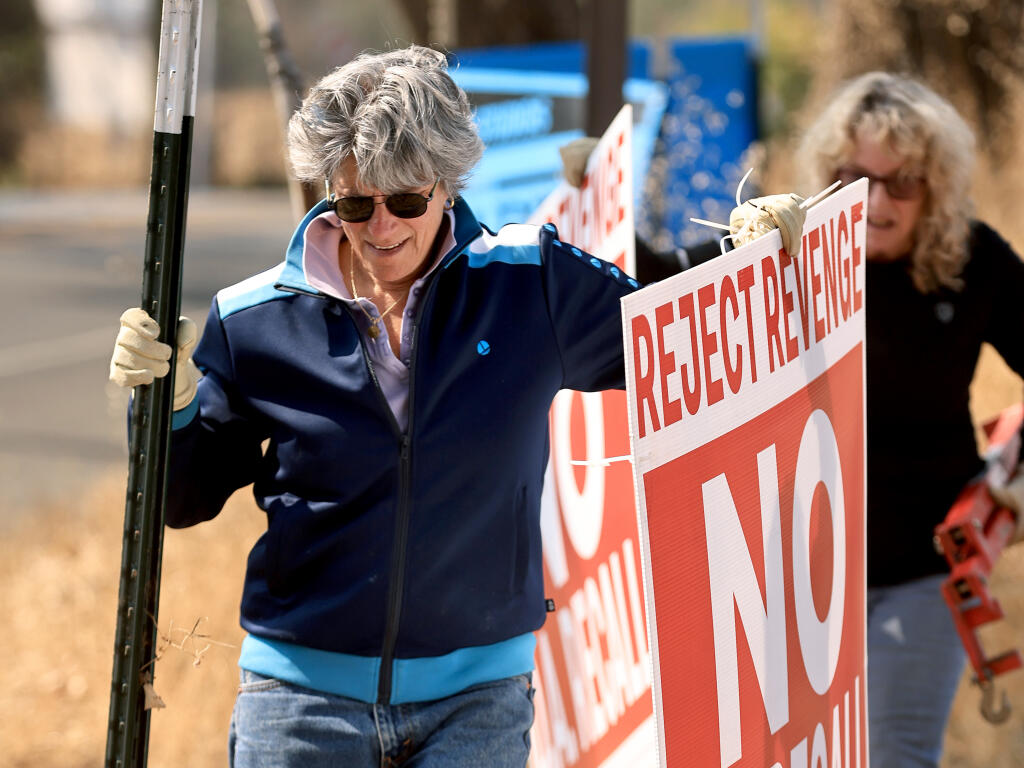 Sonoma County District Attorney Jill Ravitch, with the help of Maddy Hirshfield, right, spent part of Wednesday along Highway 12 in Santa Rosa removing her campaign signs after taking in an overwhelming majority of votes to defeat the recall Tuesday night. (Kent Porter / The Press Democrat)