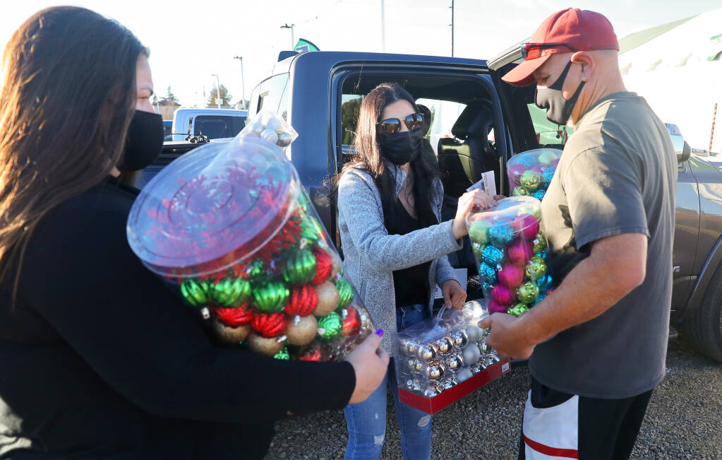 Tory Crowder, center, and her father, Dave Puentes, provide Christmas trees and ornaments to Sara Gonzales for women with children housed by Women's Recovery Services, at Mark's Christmas Tree Lot in Santa Rosa on Monday, Dec. 7, 2020. (Christopher Chung / The Press Democrat)