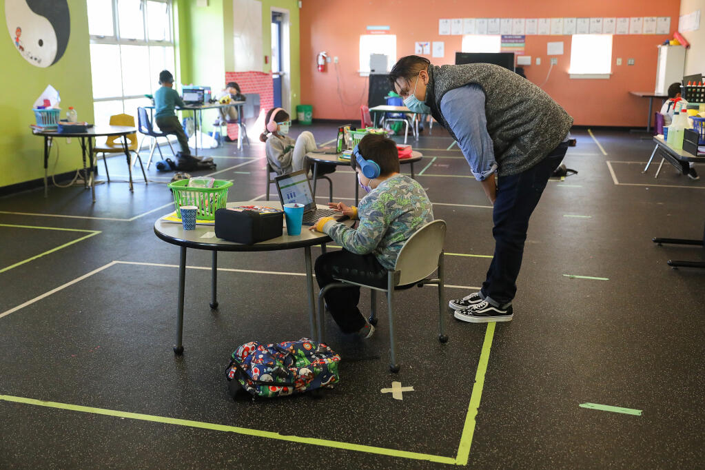 Staff member Brayan Martinez, right, helps a student at the club in January. Children have been put in pods and socially distanced during the pandemic. (Christopher Chung/ The Press Democrat)