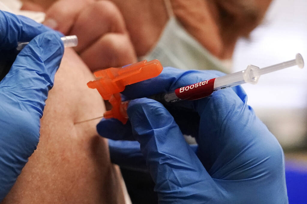 FILE - A pharmacist injects a patient with a booster dosage of the Moderna COVID-19 vaccine at a vaccination clinic in Lawrence, Mass., on Wednesday, Dec. 29, 2021. (AP Photo/Charles Krupa, File)