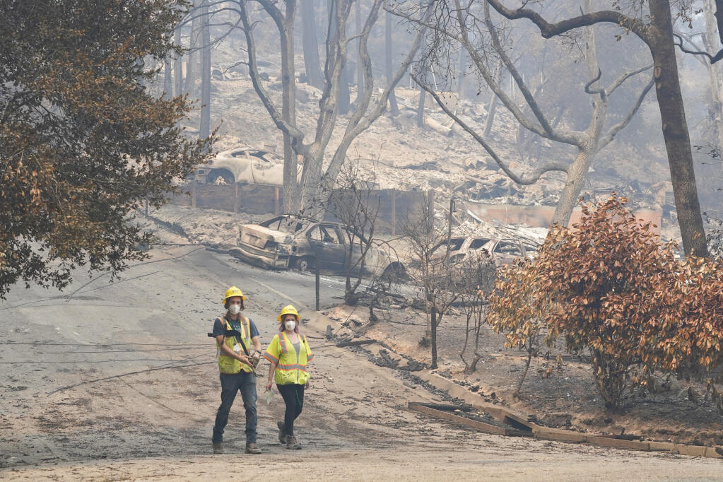 Workers with Davey Resource Group asess the damage to the trees in a neighborhood Tuesday, Aug. 25, 2020, in Boulder Creek, Calif.,after the the CZU August Lightning Complex Fire passed by. (AP Photo/Marcio Jose Sanchez)