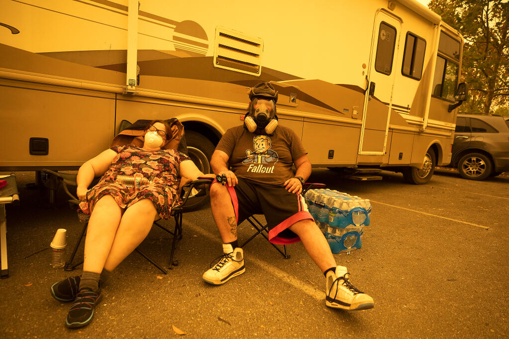 Crickett, left, and Josh Green try and get some sleep on Monday morning, Sept. 28, 2020, in the parking lot of A Place to Play in Santa Rosa. The pair evacuated their Los Alamos Road home with their extended family last night as the Glass fire approached.  (John Burgess/The Press Democrat)