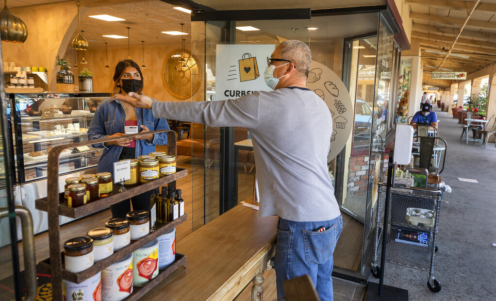 Patrick Vidano orders a selection of pastries from Aymara Myers at the Village Bakery in Montgomery Village on Tuesday, March 30, 2021. Vidano says he likes what new stores, like the Village Bakery, have to offer and looks forward to new ownership.  (John Burgess/The Press Democrat)