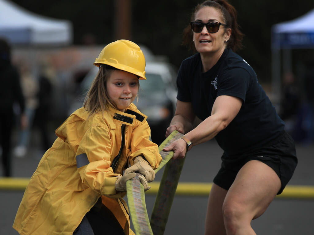Nine year-old Molly Fabian of Sonoma gets hands-on experience and professional tutelage from Santa Rosa Fire Department firefighter/engineer Jessie Taintor during the Women's Public Safety Day at the SRFD training tower, Saturday, March 5, 2022 in Santa Rosa (Kent Porter / The Press Democrat) 2022