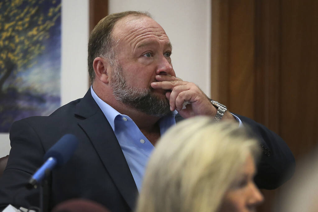 Alex Jones attempts to answer questions about his text messages asked by Mark Bankston, lawyer for Neil Heslin and Scarlett Lewis, during trial at the Travis County Courthouse in Austin, Wednesday Aug. 3, 2022. Jones testified Wednesday that he now understands it was irresponsible of him to declare the Sandy Hook Elementary School massacre a hoax and that he now believes it was “100% real." (Briana Sanchez/Austin American-Statesman via AP, Pool)