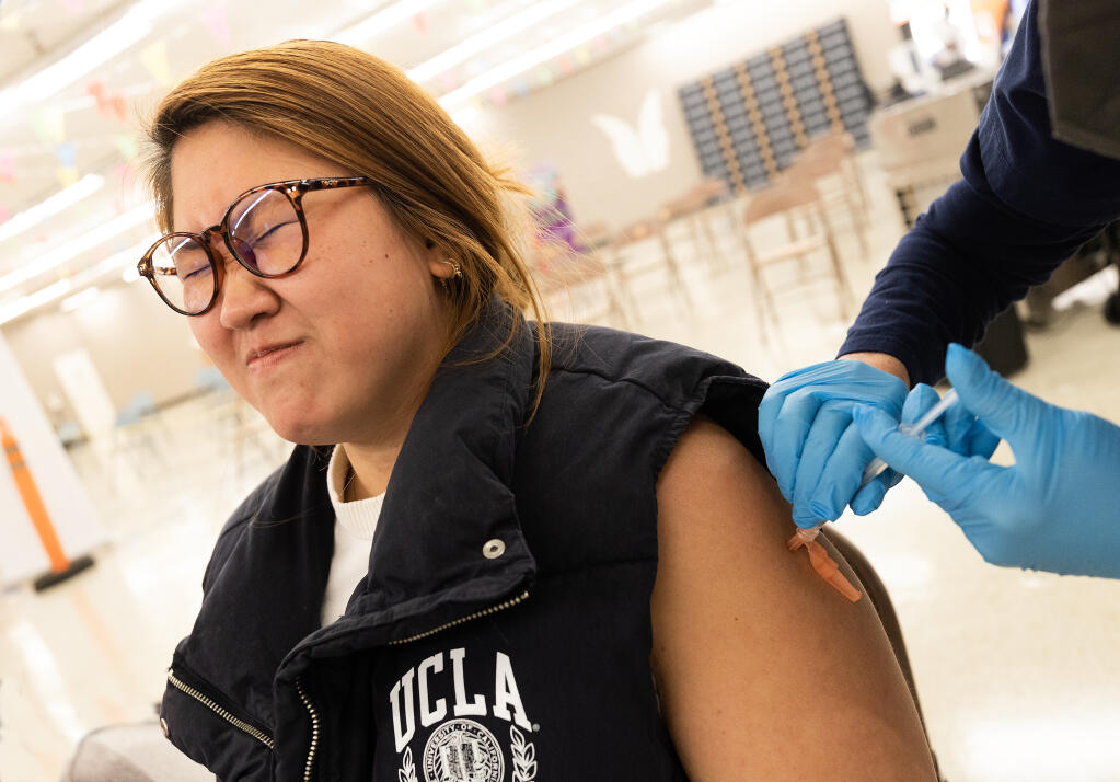 Martina Basquez, who hates needles, receives her flu shot at the Roseland Community Clinic Wednesday, November 16, 2022.    (John Burgess/Press Democrat)