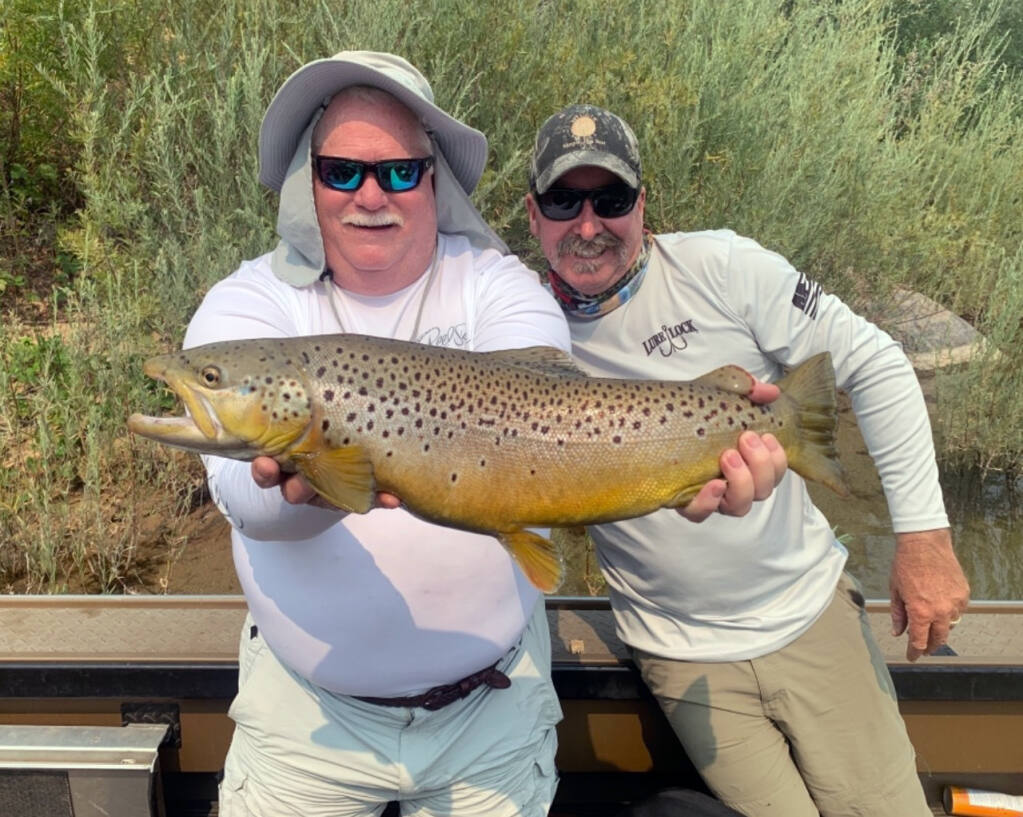 GUIDE KIRK PORTOCARRERO (right) and his client show off this big brown trout caught on the lower Sacramento River in early Auguts, 2021, near Redding. It measured 28 inches. (Submitted)