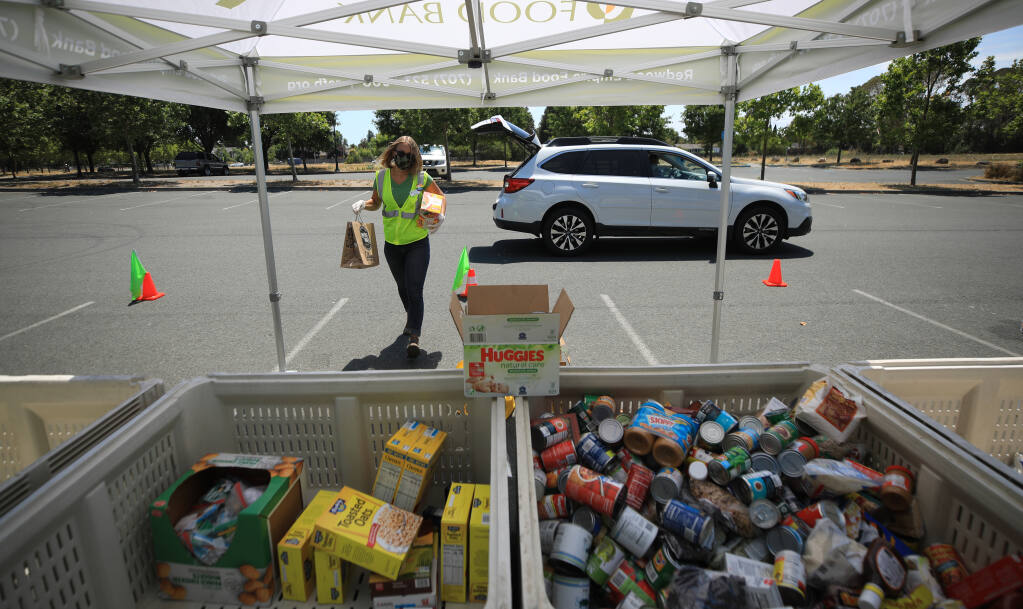 Cassidy Jourdan of the Redwood Empire Food Bank takes in donated grocery items, Wednesday, July 22, 2020 at a Place to Play in Santa Rosa. (Kent Porter / The Press Democrat) 2020