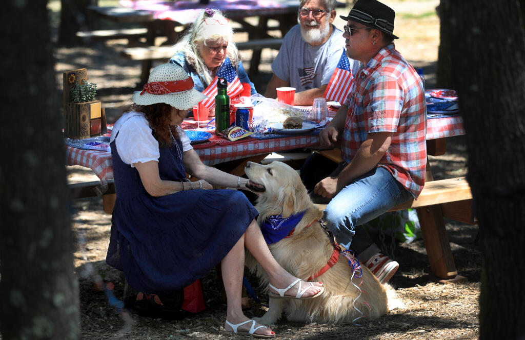 Diane Shaw gives attention to her 4-year-old golden retriever, Brooke, as her husband, Joshua Shaw, relaxes Saturday, July 2, 2022, during a holiday gathering of Forestville and Sonoma County residents for a barbecue in Forestville. In the background are Mary Jo and Gordon Evans. (Kent Porter / The Press Democrat) 2022