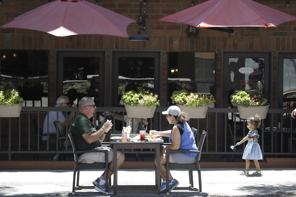 FILE - In this July 18, 2020 file photo, patrons eat at table set up on a sidewalk in Burbank, Calif.  (AP Photo/Marcio Jose Sanchez, File)