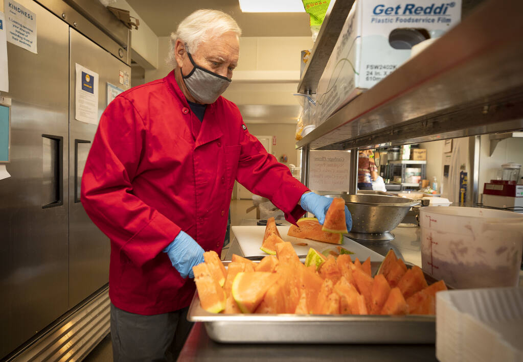 Volunteer Peter Markey cuts up watermelon for lunches for women and children in the kitchen at the Living Room in Santa Rosa on Friday, Sept. 4, 2020.  (John Burgess / The Press Democrat)