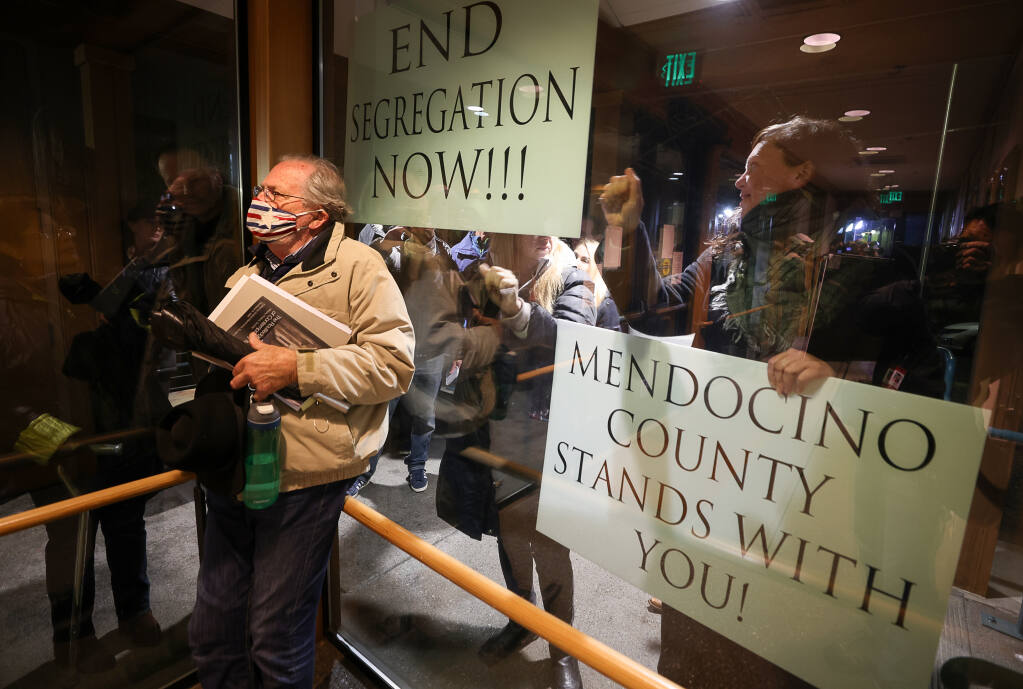 Dave Henderson, a supporter of the vaccine mandate who planned on urging the Healdsburg City Council to maintain the policy of admitting only those who could demonstrate their vaccination status to meetings, waits for the council meeting to begin, while anti-vaccination protestors bang on the windows of Healdsburg City Hall  on Monday, December 6, 2021.  (Christopher Chung/ The Press Democrat)