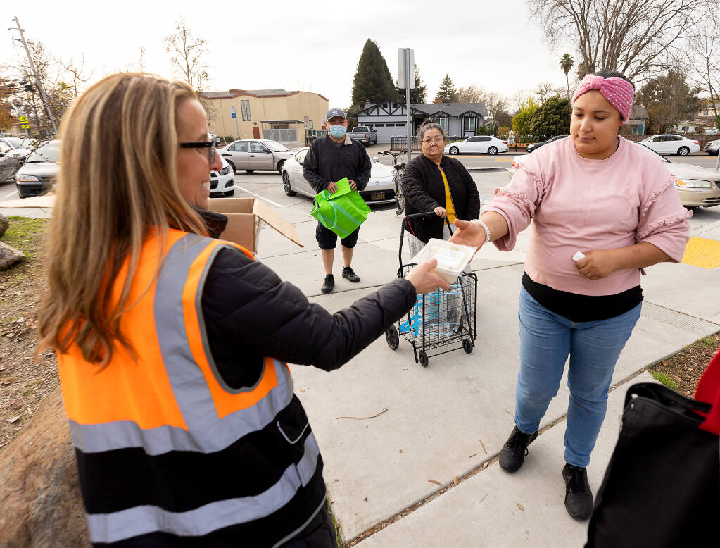 Rachelle Mesheau, left, with the Redwood Empire Food Bank passes out a Cheese Plate snack pack to Sandra Ayala at their regular food distribution site at Bayer Park in Santa Rosa Wednesday, December 21, 2022. The snack contains brie from the 1,000 wheels donated by the Marin French Cheese Co. (John Burgess/The Press Democrat)