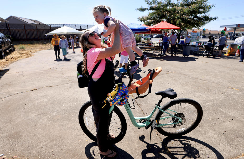 Amy Miller and her 1-year-old daughter Evelyn Miller arrive at Mark West Area Community Fund's open house on a vacant lot off Old Redwood Highway Saturday, Aug. 26, 2023, where community members are planning to build a park. The site once held a preschool, which was destroyed in the 2017 Tubbs Fire. (Kent Porter / The Press Democrat)