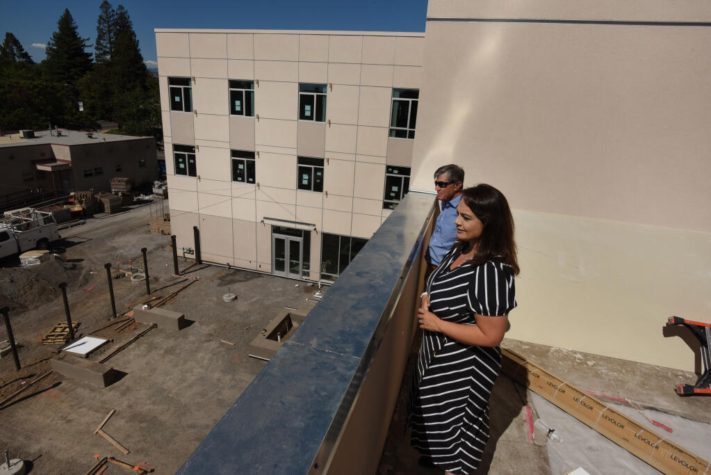 Catholic Charities CEO Len Marabella, left, and Chief Programs Officer Jennielynn Holmes look out over the construction site during a preview tour of the construction progress at Caritas Village, a 48,000 square foot family shelter, homeless drop-in center and health clinic developed by Catholic Charities and Burbank Housing and located in downtown Santa Rosa, Calif. on Friday, July 8, 2022. (Erik Castro / For The Press Democrat)