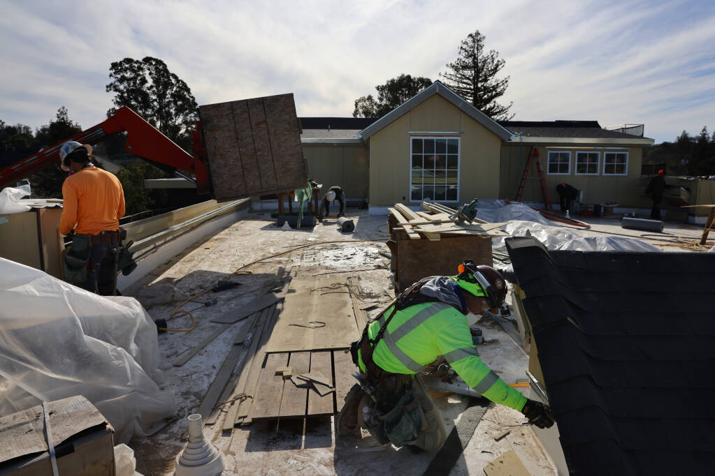 Construction workers install trim on the roof at the River City Senior Apartments, a new PEP Housing residential complex in Petaluma on Thursday, Jan. 13, 2022. (BETH SCHLANKER/THE PRESS DEMOCRAT)