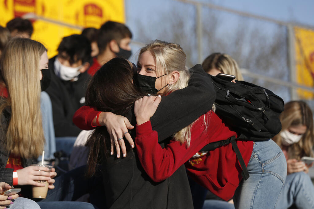 Junior Audrey Nordby, 17, hugs a classmate before a morning assembly on the first day of in-person classes for all students in the "Gold" group at Cardinal Newman High School in Santa Rosa, California, on Thursday, March 25, 2021. The other half of the student body in the "Red" group returned to in-person classes on Monday and Tuesday only, while the "Gold" group was scheduled for Thursday and Friday. All students in both groups will attend in-person classes after spring break. (Beth Schlanker/ The Press Democrat)
