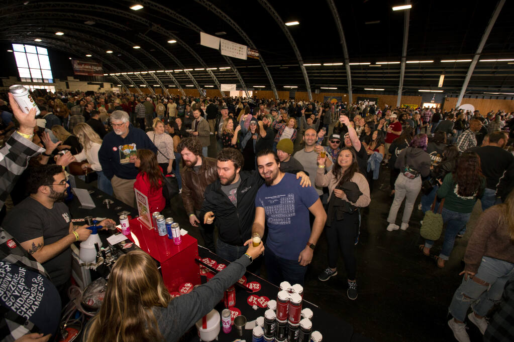 Austin Jacobs, front center right, receives a glass of beer next to friend, Aaron Burns, both of San Jose, at the Old Caz Beer line during the 26th annual Battle of the Brews at the Sonoma County Fairgrounds, Saturday, April 1, 2023, in Santa Rosa. (Darryl Bush / For The Press Democrat)