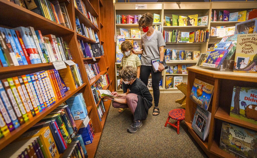 Otis Thompson with his grandmother Lynn Parry, below, and mom, Laura Fried, search the kids section for Harry Potter books at Four-Eyed Frog Books in Gualala on Tuesday, Aug. 16, 2022. (John Burgess/The Press Democrat)