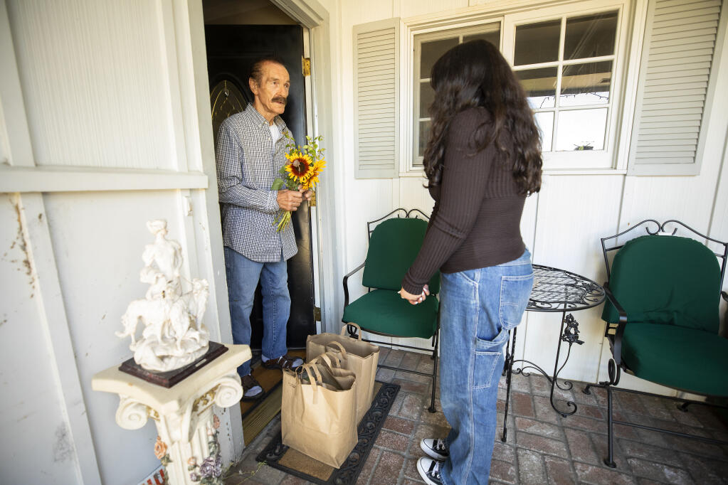 Ceres Community Project delivery angel Elise Curtis, 16, delivers meals, flowers and a hand-drawn note to a client in Santa Rosa on Aug. 19, 2022. Curtis, with the help of her driver, mom Tambra, has been delivering meals to those in need for three years. (John Burgess / The Press Democrat)