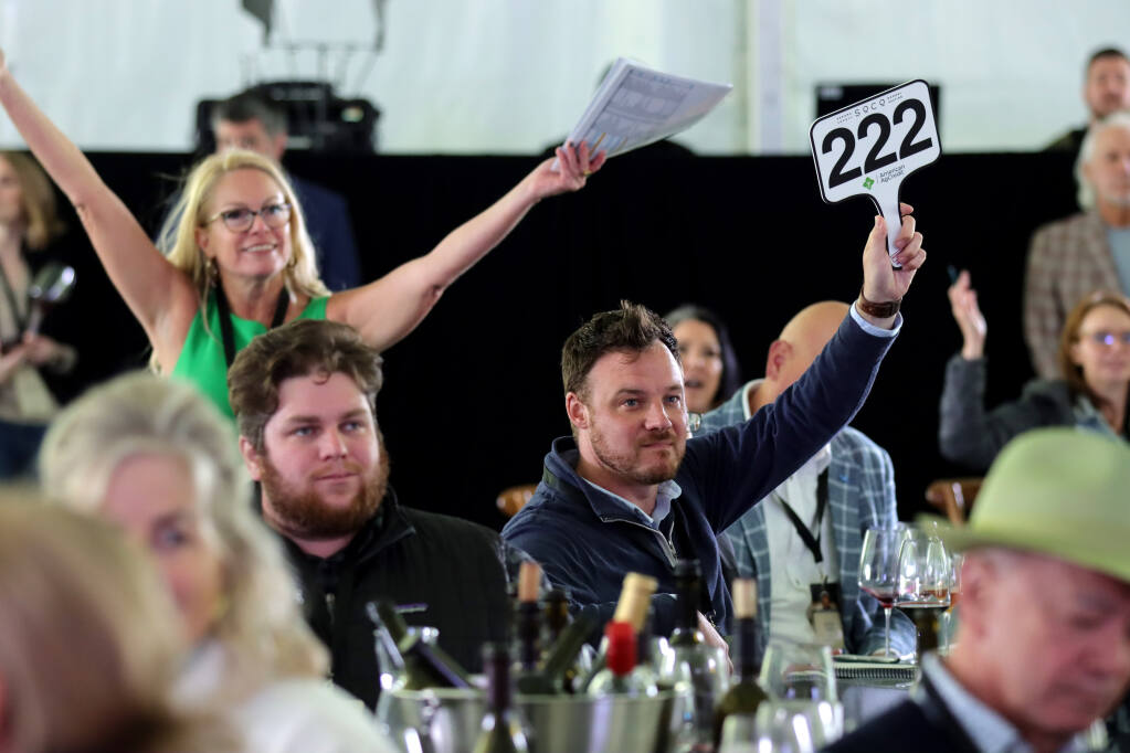 Will Bliss of H-E-B in Texas, holding up his paddle, wins a bid during the annual Sonoma County Barrel Auction at MacMurray Ranch, Friday, May 5, 2023, in Healdsburg. (Darryl Bush / For The Press Democrat file)
