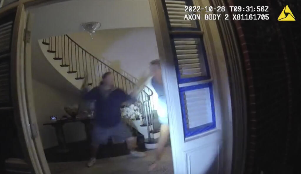In this image taken from San Francisco Police Department body-camera video, Paul Pelosi, right, the husband of former U.S. House Speaker Nancy Pelosi, fights for control of a hammer with his assailant during a brutal attack in the couple's San Francisco home on Oct. 28, 2022. The body-camera footage shows the suspect David DePape wrest the tool from the 82-year-old Pelosi and lunge toward him the hammer over his head. The blow to Pelosi occurs out of view and the officers — one of them cursing — rush into the house and jump on DePape. (San Francisco Police Department via AP)