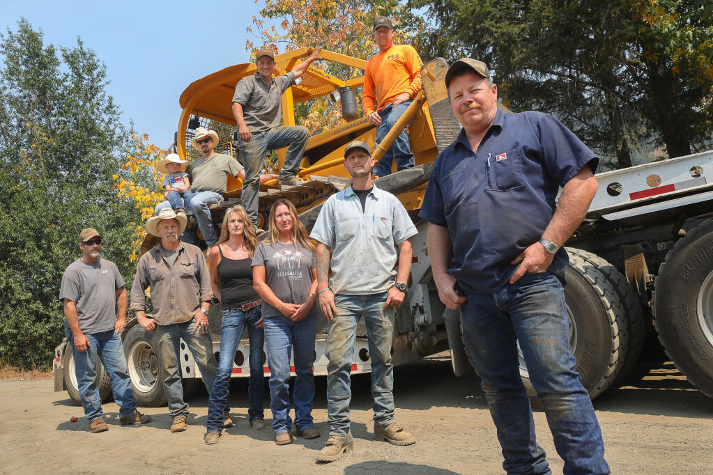 Jeff Parmeter, right, and members of the Parmeter Logging & Excavation crew, including Mike Burchfield, clockwise from bottom right, Heather Parmeter, Melinda Parmeter, Mike Parmeter, Ron Bei, William Harrison (holding his son William), Sean Nunez, and Charles Radtkey, along with many other Cazadero community members manned bulldozers and assisted to defend against the Walbridge fire. (Christopher Chung/ The Press Democrat)