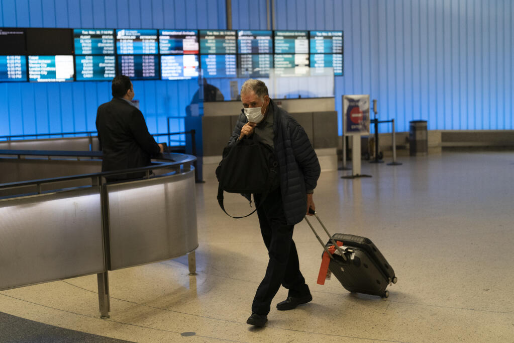 A traveler adjusts his face mask as he walks through the arrivals area at the Los Angeles International Airport in Los Angeles, Tuesday, Nov. 30, 2021. (AP Photo/Jae C. Hong)