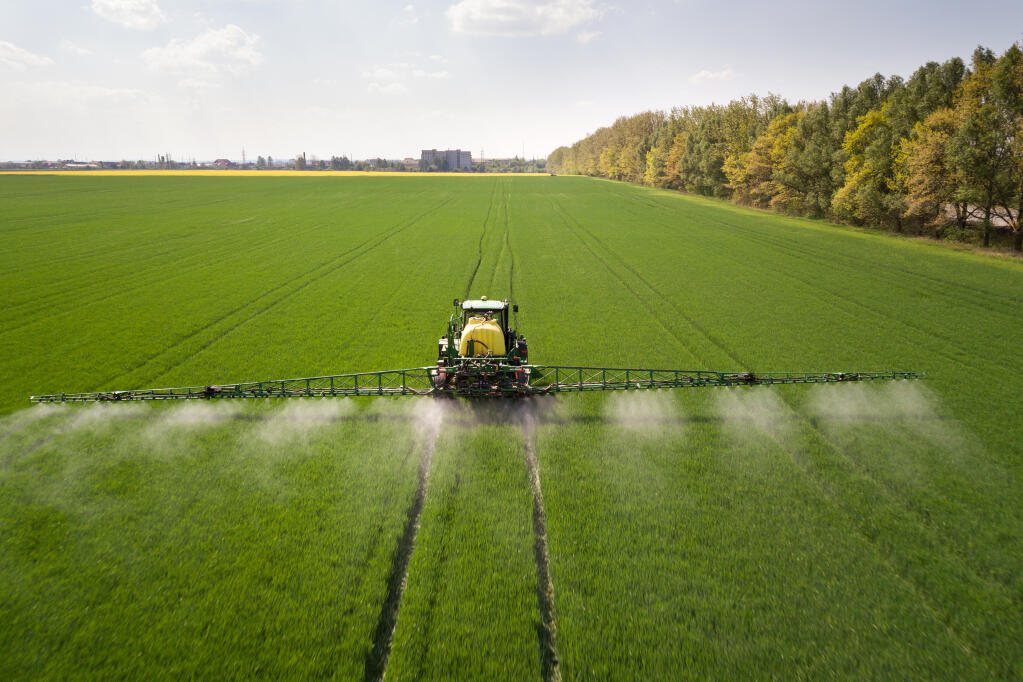 Tractor sprays chemical pesticides on the large green agricultural field at spring. (Brian Lilla, “Children of the Vine”)
