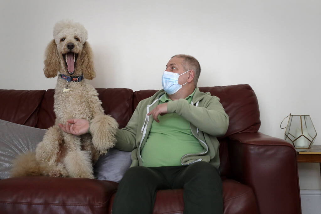 Long-COVID patient Gary Miller sits on his sofa at home with his dog Rupert in London, May 11. For taxi driver Miller, recovery is agonizingly slow. He says there are times "I feel like I'm taking one step forward, and then all of a sudden — bang — I'm ill again and I take two steps back." (AP Photo/Kirsty Wigglesworth)