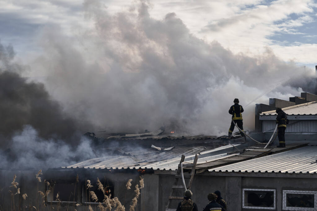 Ukrainian State Emergency Service firefighters put out the fire after the Russian shelling hit an industrial area in Kherson, Ukraine, Friday, Feb. 3, 2023. (AP Photo/LIBKOS)