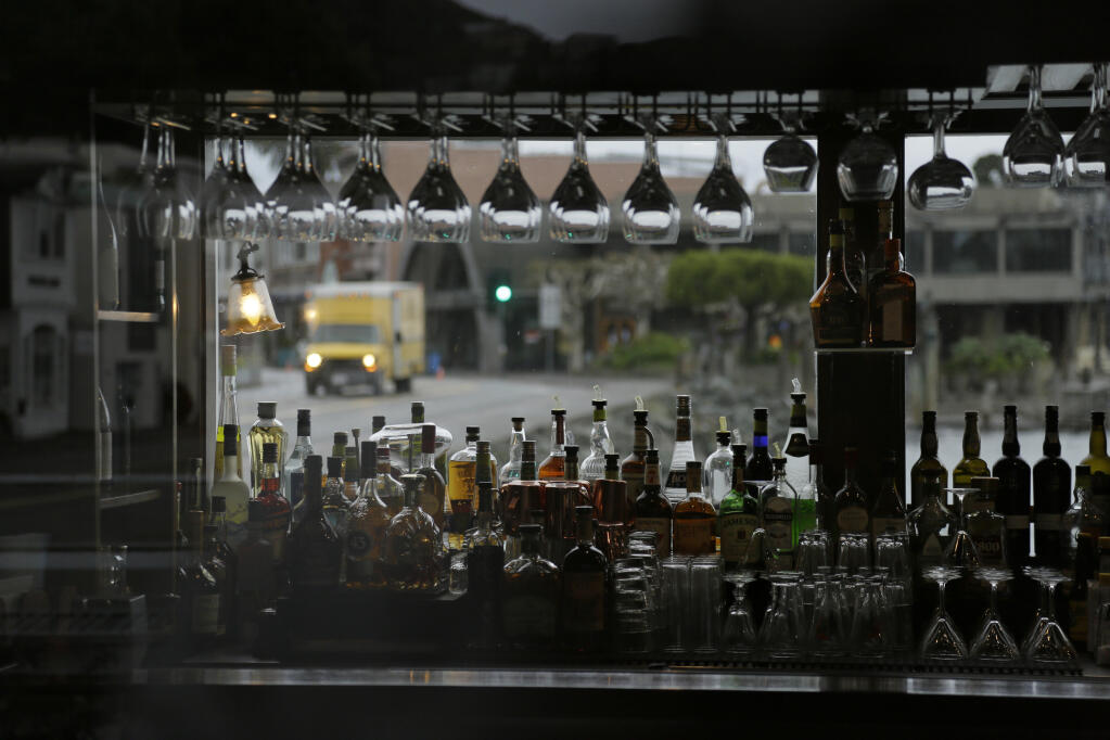 Framed by liquor bottles and and glasses in the closed Scoma's restaurant, a bread truck makes a delivery in the background March 18 in Sausalito. Limited indoor dining was to return to Marin County after six months, but California officials determined local COVID-19 metrics were still too high. (AP Photo/Eric Risberg)