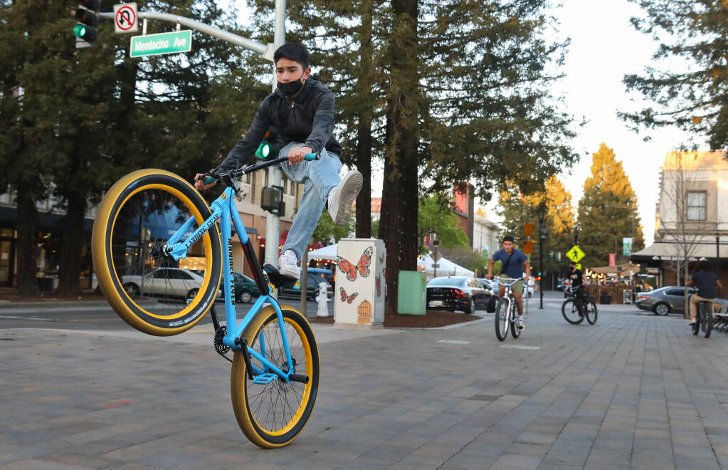 Alan Cortes and his friends perform tricks on their bikes while riding around Old Courthouse Square in Santa Rosa on Thursday, March 4, 2021.  (Christopher Chung / The Press Democrat)