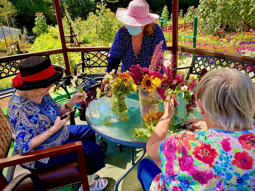Residents of Healdsburg Senior Living gather on the patio for flower arranging. Some residential facilities for elders don’t have outdoor space for residents weary of sheltering indoors. (Tony Fisher)