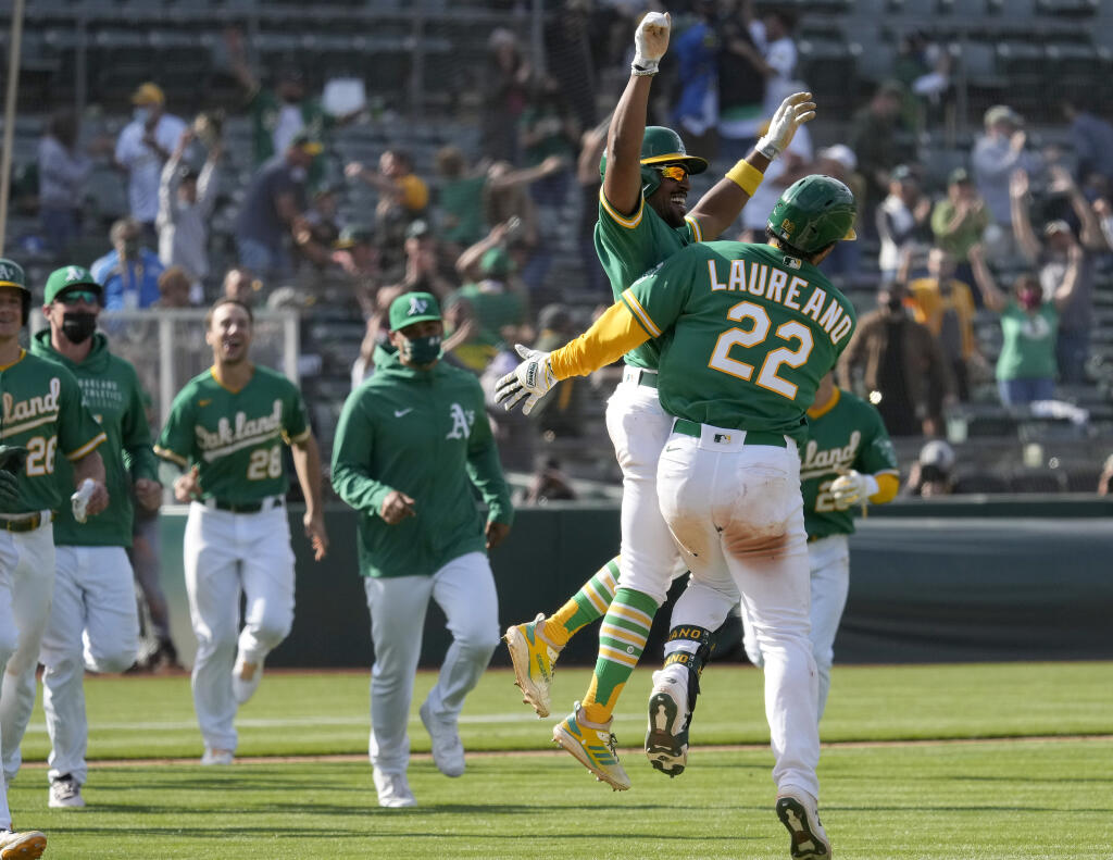 The Oakland Athletics’ Ramon Laureano, right, celebrates with Tony Kemp and teammates after two runs scored on a throwing error by Minnesota Twins third baseman Luis Arraez during the 10th inning on Wednesday, April 21, 2021, in Oakland. Oakland won 13-12. (Tony Avelar / ASSOCIATED PRESS)