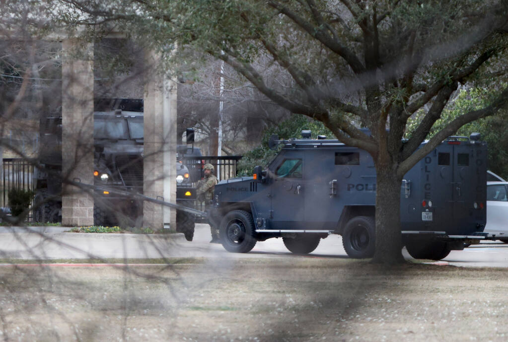 Law enforcement teams stage near Congregation Beth Israel while conducting SWAT operations in Colleyville, Texas on Saturday afternoon, Jan. 15, 2022. Authorities said a man took hostages Saturday during services at the synagogue where the suspect could be heard ranting in a livestream and demanding the release of a Pakistani neuroscientist who was convicted of trying to kill U.S. Army officers in Afghanistan. (Elias Valverde/The Dallas Morning News via AP)