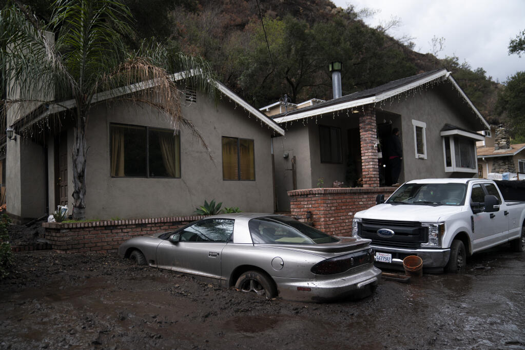 A vehicle is partially submerged in mud following mudslides in Silverado Canyon, Calif., Wednesday, March 10, 2021. A Pacific storm brought more much-needed rain and snow to California on Wednesday at the tail-end of a largely dry winter. Winter storm warnings were in effect in the southern Cascades, down the length of the Sierra Nevada and the mountains of Southern California, the National Weather Service said. (AP Photo/Jae C. Hong)